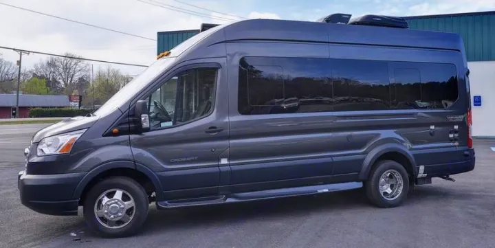 A dark gray, high-top RV rental, converted from a van, is parked. Ideal for travel or camping.. Coachmen CrossFit 22c 2019