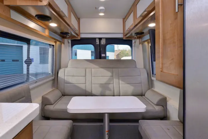 Spacious RV rental interior featuring a gray U-shaped lounge, dining table, and overhead storage. Ideal for travel comfort.. Coachmen CrossFit 22c 2019