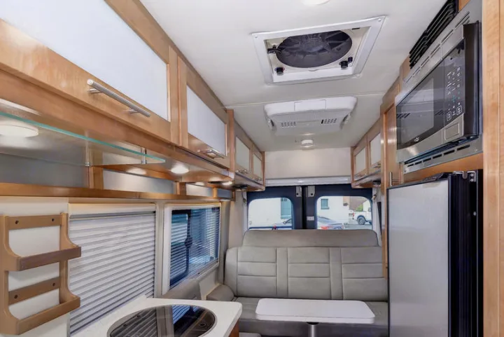 Bright rv rental interior: compact kitchen, microwave, fridge, comfortable seating, and overhead cabinets for travel.. Coachmen CrossFit 22c 2019