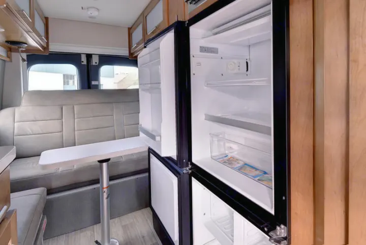 Spacious RV rental interior featuring a dinette, bench seating, and open refrigerator for easy access.. Coachmen CrossFit 22c 2019