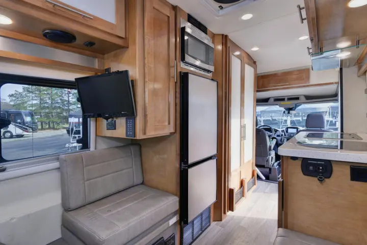 RV rental interior: kitchen, fridge, microwave, TV, and bench seat define this compact living space.. Coachmen CrossFit 22c 2019