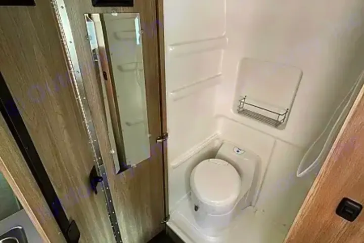 Compact RV rental bathroom: features a white toilet, integrated shower, and mirror.. Winnebago Solis 2023