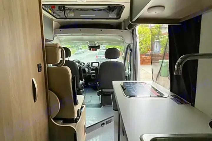 View inside a modern RV rental. This camper van features a well-equipped kitchen, comfortable seating, and a clear view to the front.. Winnebago Solis 2023