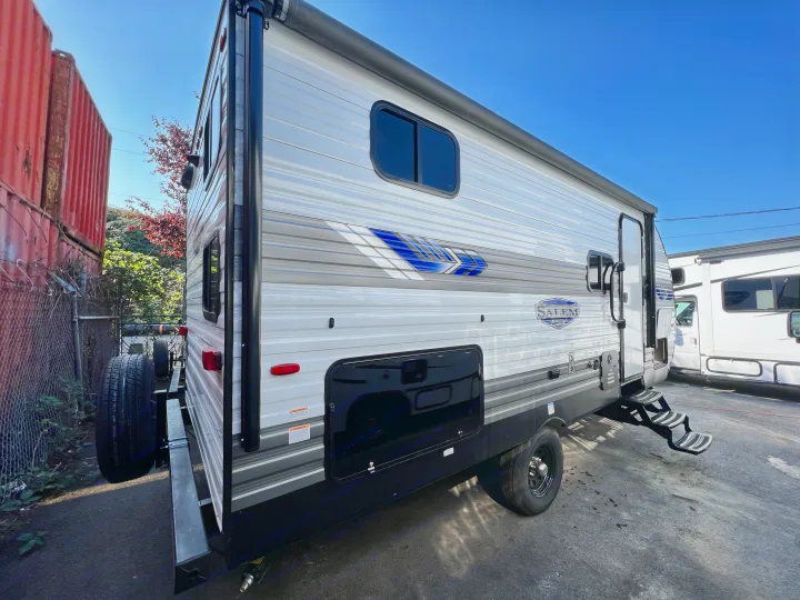 Side view of a white & gray travel trailer (RV rental) with blue graphics, open door & steps. Parked outside.. Forest River Salem Cruise Lite 2024