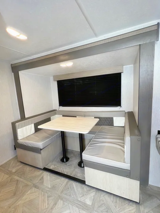 Experience this RV rental's modern dinette: cozy gray/white booth seating, light table, and dark window blinds.. Forest River Salem Cruise Lite 2024