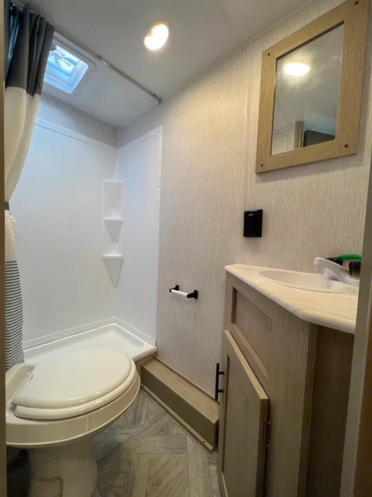 Compact RV rental bathroom: features shower, toilet, sink vanity. Brightly lit, functional design for travel.. Forest River Salem Cruise Lite 2024