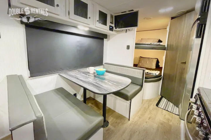 Cozy RV rental interior featuring a dinette, kitchen, and bunk beds, offering a comfortable living space for your adventures.. Heartland Trail Runner 2021