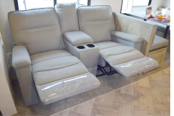 Comfortable grey reclining RV rental seating with cup holders and a dinette in the background. Perfect for relaxation.. Puma Palomino 2021