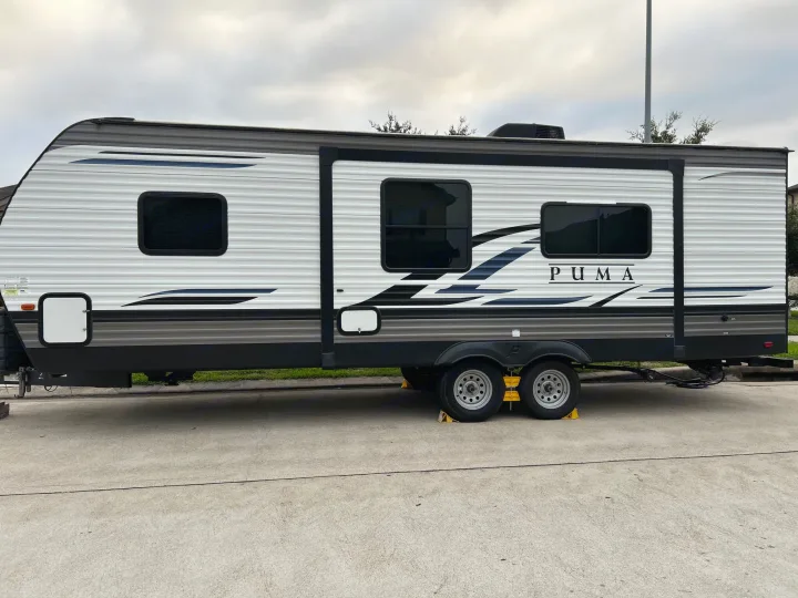 White & grey Puma travel trailer, a great rv rental choice, parked on concrete under a cloudy sky.. Puma Palomino 2021