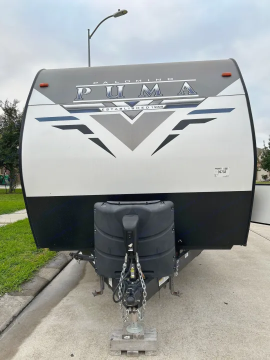 Head-on view of a grey and white Palomino Puma travel trailer, ideal for an rv rental. Shows hitch & propane tank.. Puma Palomino 2021