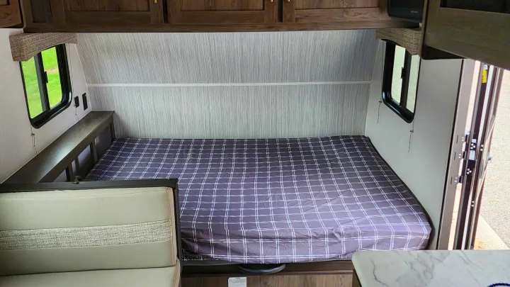 Cozy RV rental interior showcasing a large plaid bed, dinette, and windows, ideal for a comfortable camper setup.. Forest River Viking Ultra Lite 2022