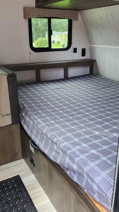 RV rental interior: Cozy bed with a plaid mattress, window view, and wall outlets in this compact camper.. Forest River Viking Ultra Lite 2022