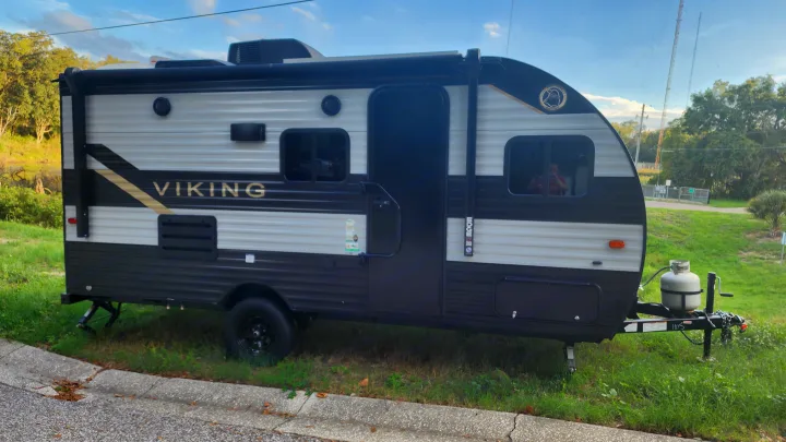 Black and white Viking travel trailer, equipped with a propane tank, ready for your RV rental adventure.. Forest River Viking Ultra Lite 2022