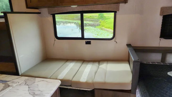 RV rental interior features a convertible bed, large window with a serene lake and lily pad view.. Forest River Viking Ultra Lite 2022