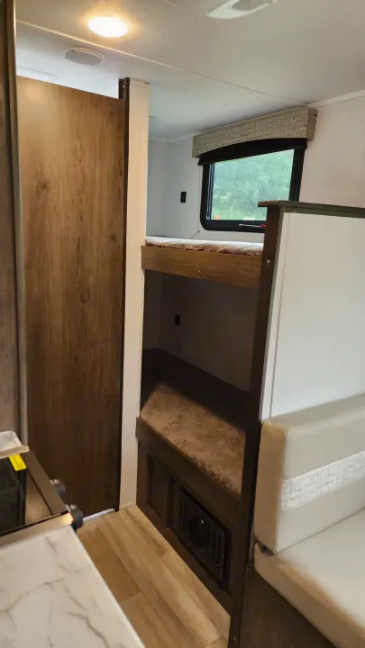 This RV rental interior highlights bunk beds, a dinette area, and part of the kitchen, ideal for travel.. Forest River Viking Ultra Lite 2022