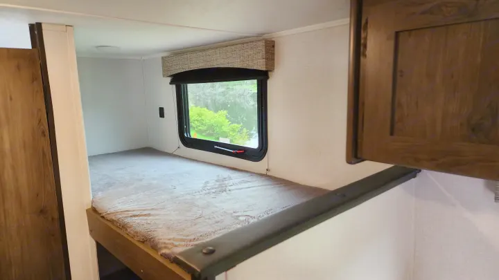 RV rental bunk bed with plush grey blanket and window offering a view of water and trees.. Forest River Viking Ultra Lite 2022