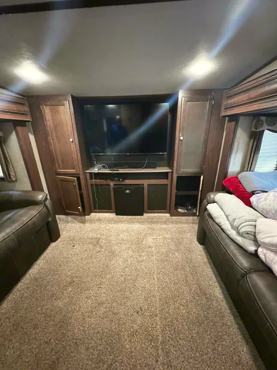 RV rental living area with entertainment center, TV, comfy sofas, and carpet, ready for your road trip comfort.. Keystone RV Sprinter 2018