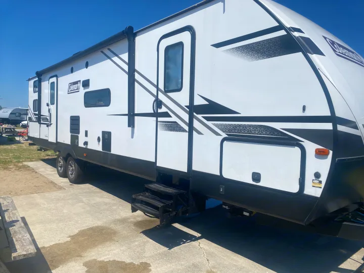 This Coleman RV rental, a white travel trailer with solar, is parked on a sunny pad, ready for adventures.. Dutchmen Coleman Light 2022