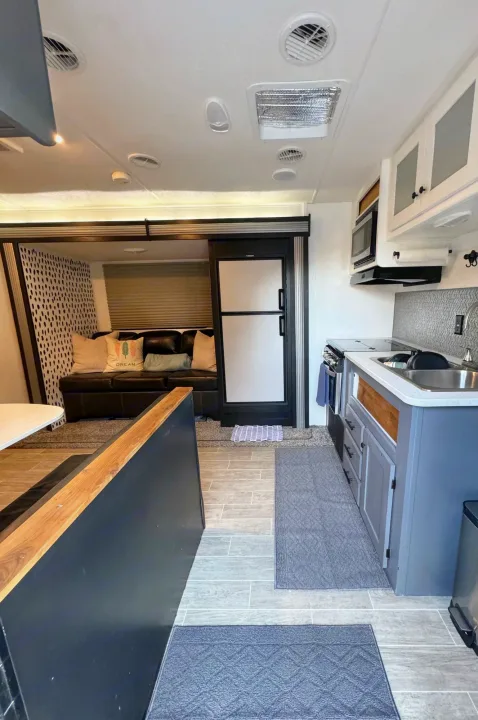 This rv rental offers a modern kitchen, spacious living area with couch, and a fridge. Perfect for road trips!. Heartland RVs Trail Runner 2020