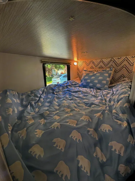 RV rental bedroom view: a cozy bed with blue polar bear bedding and a patterned headboard.. Heartland RVs Trail Runner 2020