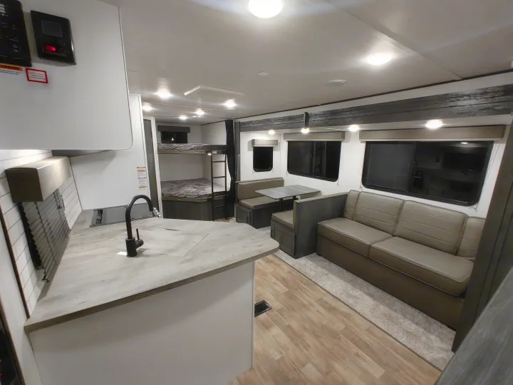 Spacious RV rental interior featuring a kitchen, bunk beds, dinette, and sofa for comfortable travel.. Keystone RV Hideout 2023