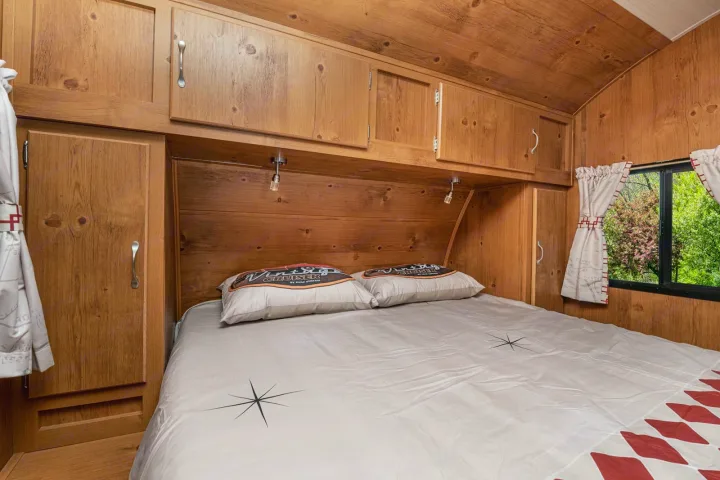 Cozy wood-paneled RV rental bedroom with a comfy bed & cabinets. Your adventure awaits!. Gulf Stream Cruiser 2021