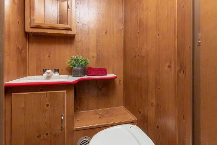 Compact, wood-paneled RV rental bathroom features a sink, cabinet, and partial toilet area.. Gulf Stream Cruiser 2021
