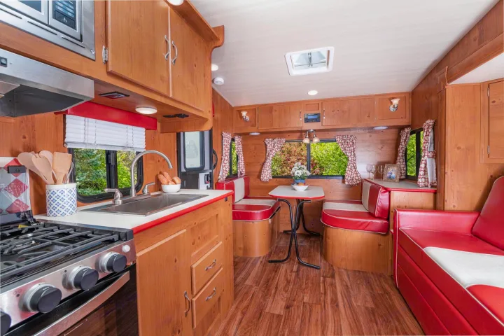 Explore this vibrant vintage RV rental, featuring a full kitchen, red & white dinette, and cozy wood interior.. Gulf Stream Cruiser 2021