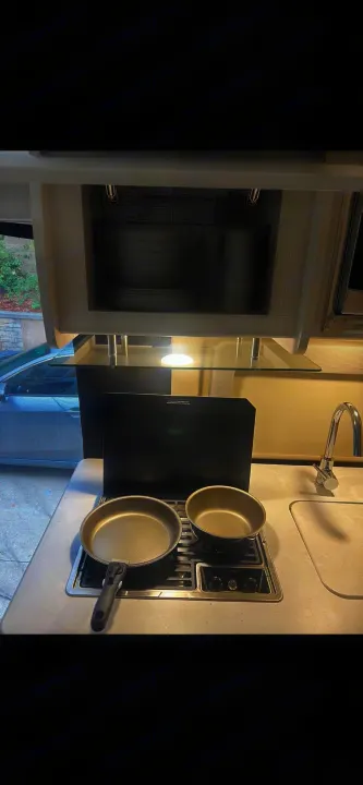 RV rental kitchen: dishes in overhead cabinet, pan & pot on 2-burner Dometic stovetop, sink. Ready for cooking!. Thor Motor Coach Other 2023
