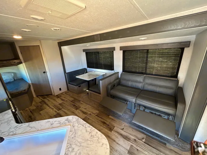 Explore this cozy RV rental's living space: dinette, reclining sofa, kitchen sink, and bunk area.. Coleman Lantern lt 2023