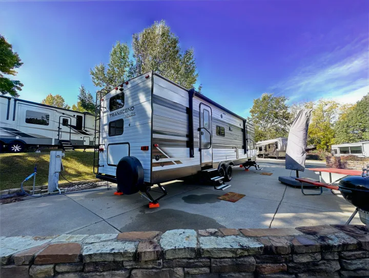 Spacious travel trailer RV set up at a sunny campsite with amenities, perfect for an RV rental getaway.. Grand Design Transcend Xplor 2022