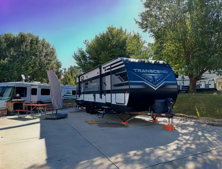 A modern Transcend travel trailer and a motorhome parked at a sunny RV site, ready for an RV rental getaway.. Grand Design Transcend Xplor 2022