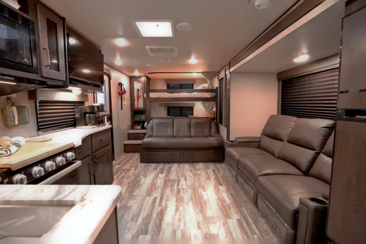 Spacious RV rental interior featuring a full kitchen, comfortable living area with recliners, and bunk beds.. Grand Design Transcend Xplor 2022