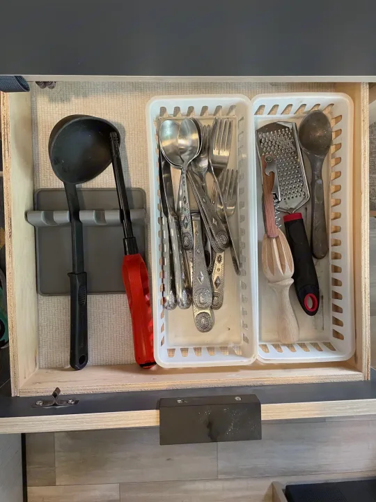 Organized kitchen drawer in an RV rental, showing a ladle, silverware, grater, reamer, and other compact tools.. Cruiser RV Hitch 16RD 2022