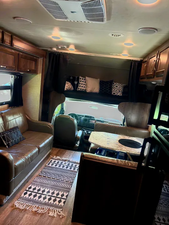 Interior of a spacious rv rental showcasing a comfortable living area with sofa, front bunk, and dining space.. Jayco Redhawk 2018