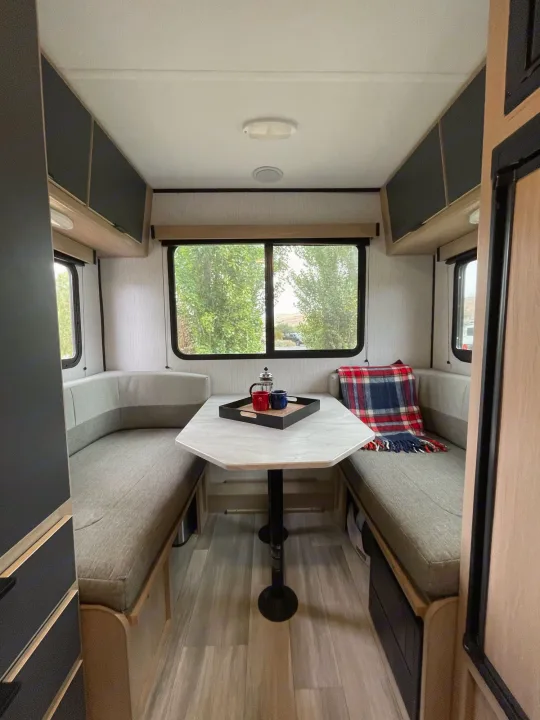 RV rental dinette setup: Comfortable U-shaped seating, central table, and scenic windows for your next adventure.. Cruiser RV Hitch 16RD 2022