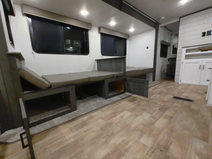 Spacious RV rental interior featuring versatile bench seating with under-storage, light wood-look flooring, and large windows.. Keystone RV Hideout 2023