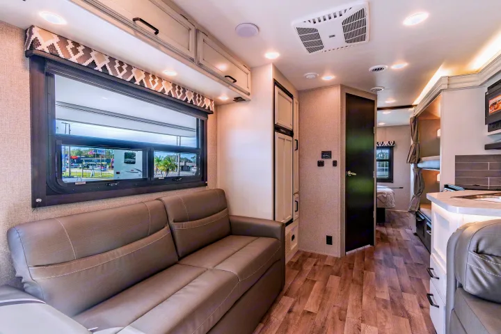 Spacious RV rental interior with sofa, kitchen, and bunk beds, ideal for travel adventures.. Jayco Redhawk 2022