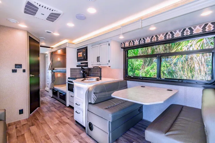 RV rental interior: modern kitchen, comfortable dinette with bench seating, bunk beds, and large scenic window.. Jayco Redhawk 2022