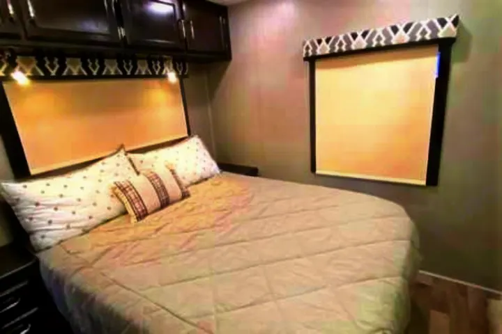 Enjoy a cozy RV rental bedroom with a comfortable bed, overhead storage, and a large window. Perfect for your travels.. Jayco Redhawk 2022