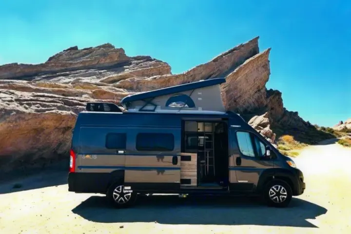 Experience adventure with this grey Solis camper van rv rental parked by unique rock formations in a sunny desert landscape. Pop-top raised.. Winnebago SOLIS 59 PX 2023
