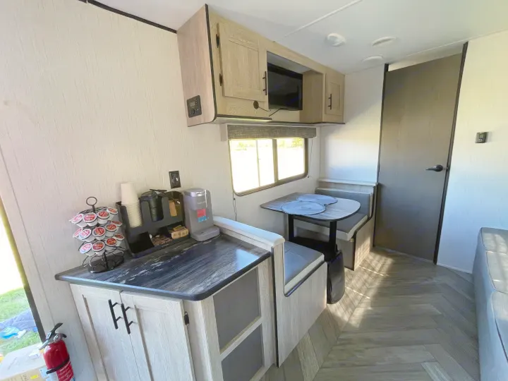 Modern RV rental interior showcasing a compact kitchen with coffee station and cozy dinette seating area.. Heartland RVs Prowler 2022