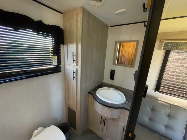 RV rental interior showing a clean bathroom with sink, light wood vanity, toilet, and multiple storage cabinets.. Heartland RVs Prowler 2022