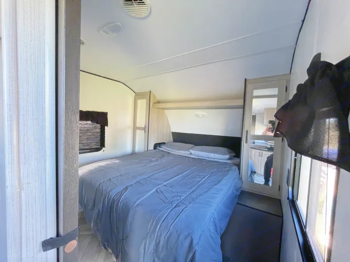 Cozy RV rental bedroom with a comfy bed, window, and mirrored closet. Perfect for travel adventures.. Heartland RVs Prowler 2022