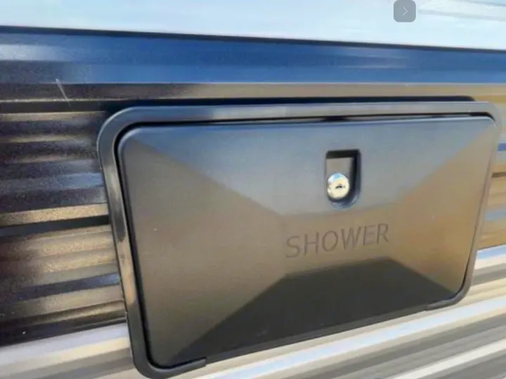 Black outdoor shower access panel with 'SHOWER' text on a grey, corrugated RV rental side.. Jayco Jay Flight 264BH 2024