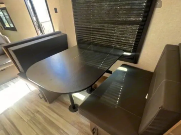 RV rental's compact dinette area, featuring a dark table and two bench seats for comfortable dining.. Jayco Jay Flight 264BH 2024