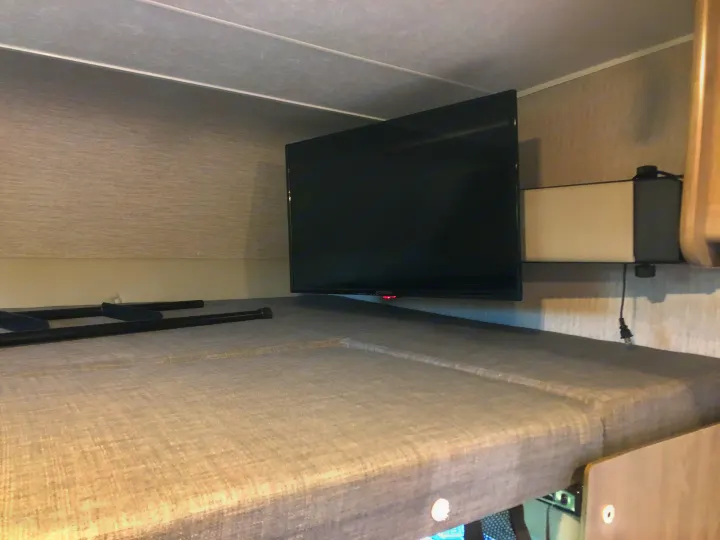 Compact RV rental bunk bed with mounted TV, offering a cozy sleeping area and entertainment. Perfect for travel.. Forest River Coachmen Freelander Premier 2022