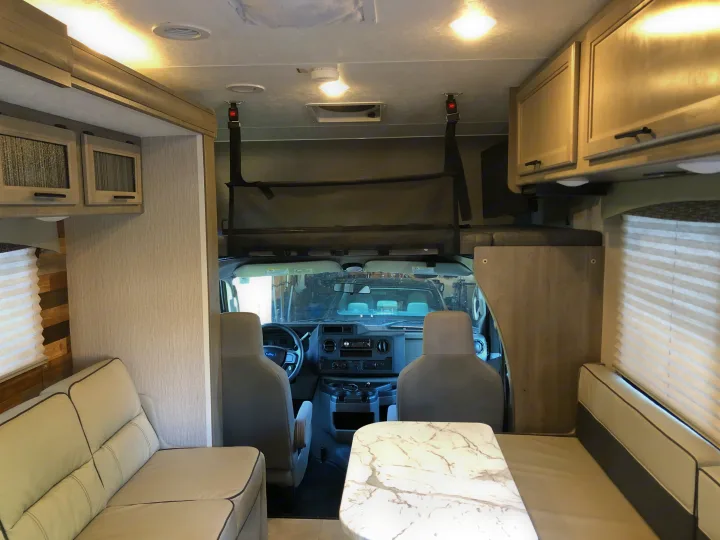 RV rental interior showing a cozy living area, driver's cab, dinette, and over-cab bunk bed.. Forest River Coachmen Freelander Premier 2022