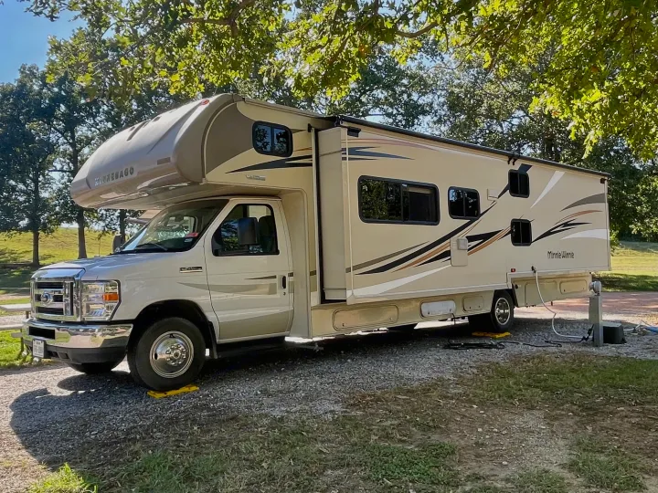This beige Winnebago Minnie Winnie RV rental is set up at a scenic campsite, ready for your next travel adventure.. Winnebago Minnie Winnie 2019