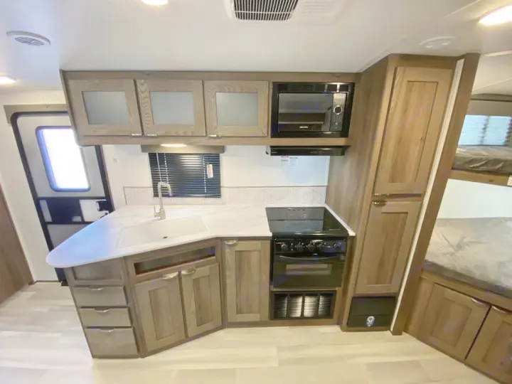 Spacious RV rental interior with modern kitchen, microwave, range, sink, and bunk beds. Perfect for family adventures.. Cruiser RV MPG Ultra Lite 2022